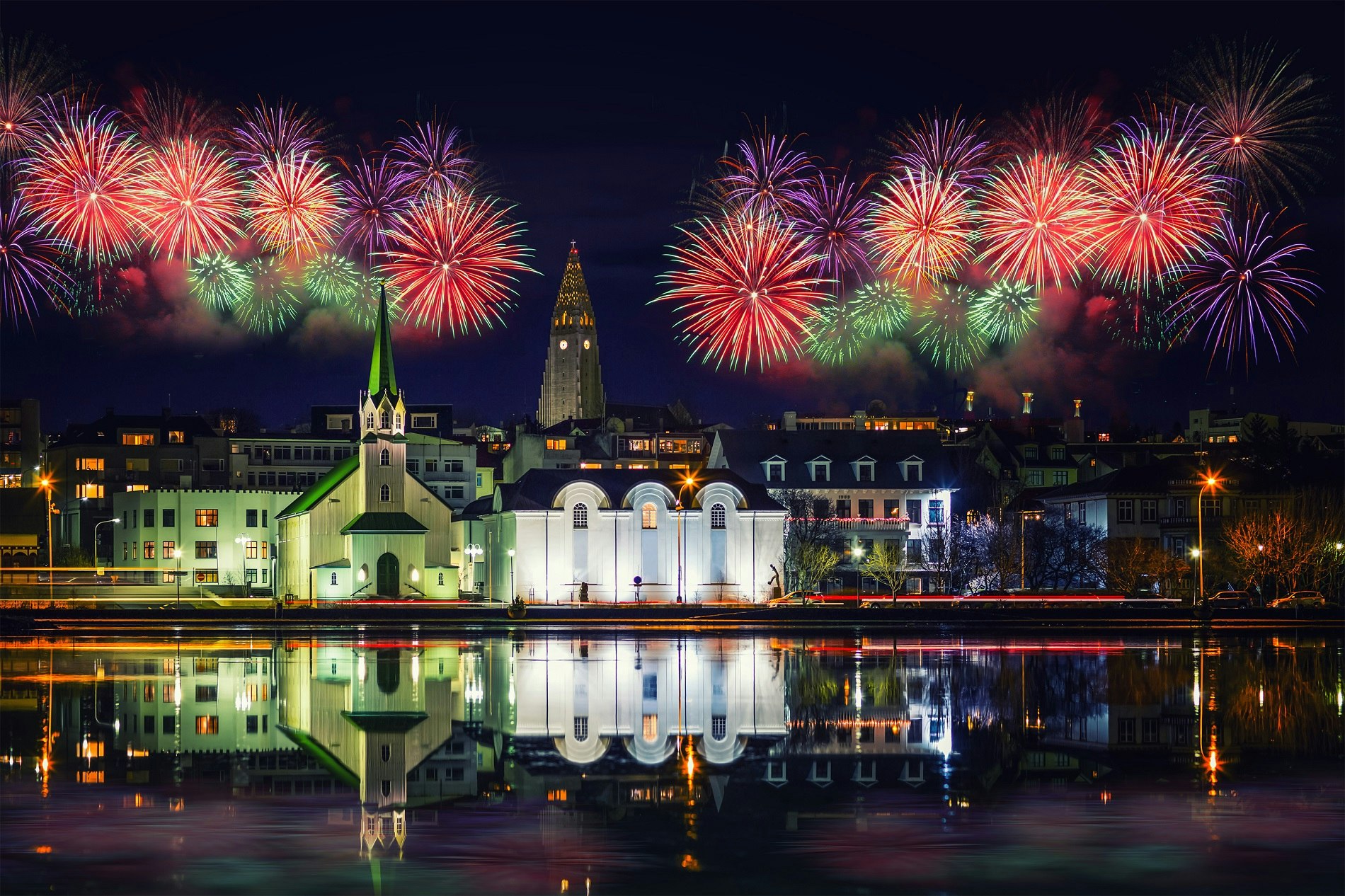 Fireworks in downtown Reykjavik with the city pond in the foreground